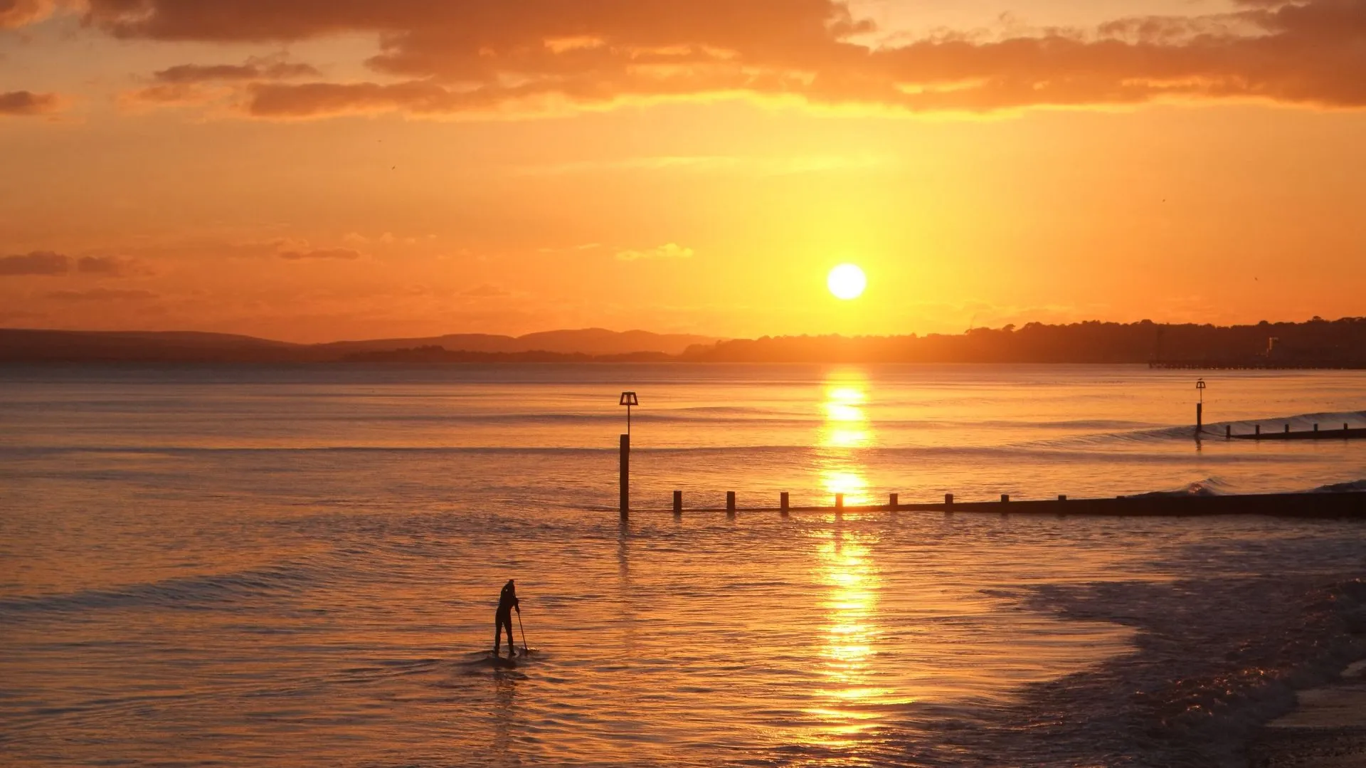 Ảnh chụp bãi biển lúc hoàng hôn với đường chân trời thẳng và mặt nước yên ả