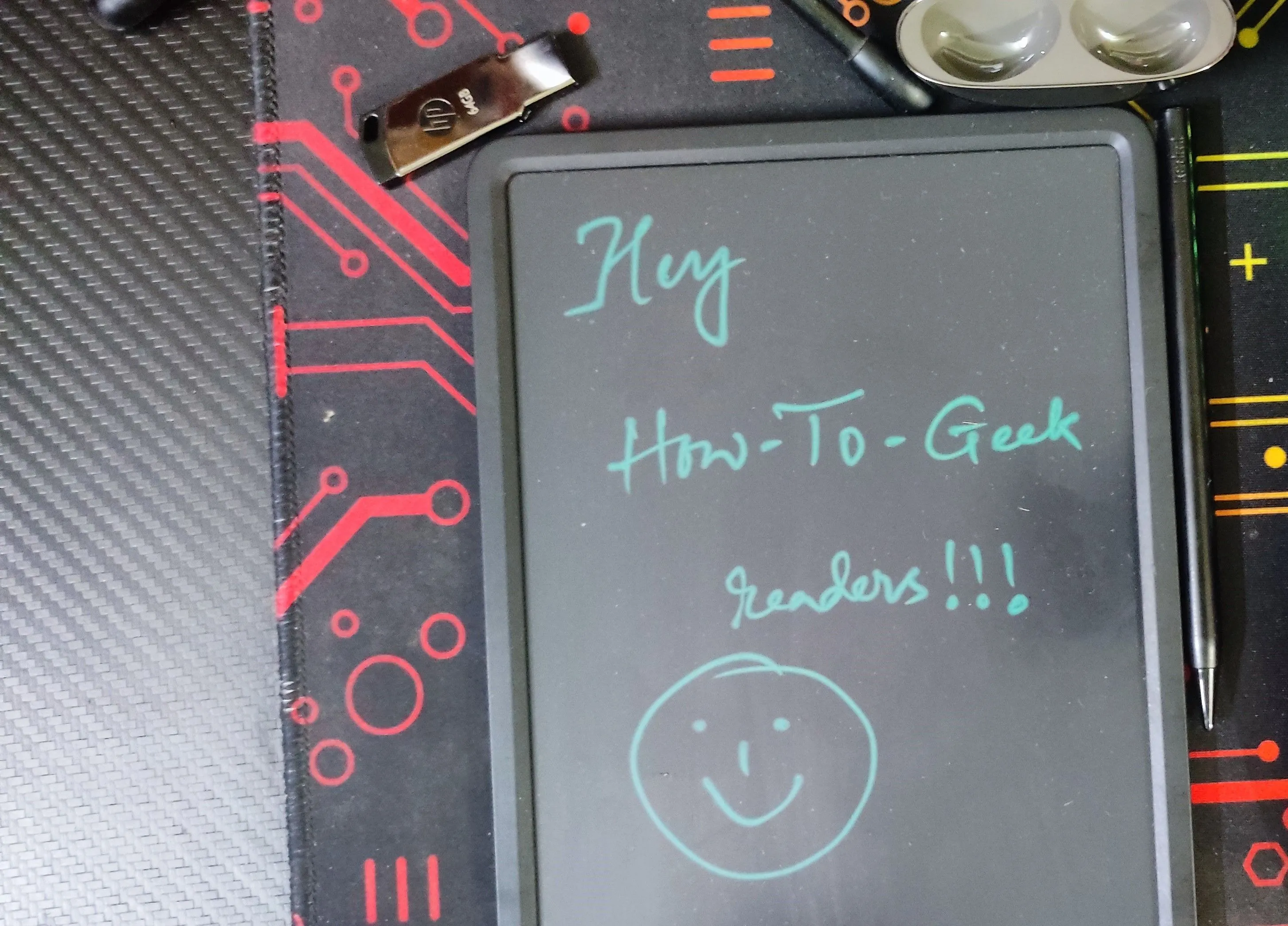Bảng vẽ điện tử LCD với thông điệp &quot;Hi to How To Geek Readers&quot; viết tay, minh họa công cụ ghi chú nhanh giúp duy trì sự tập trung.