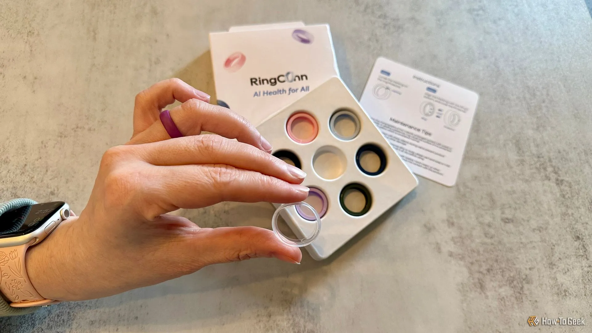 Bộ bảo vệ vòng RingConn Gen 2 Air bằng silicone và một tay đang cầm miếng dán điều chỉnh kích thước, minh họa cách bảo vệ vòng khỏi trầy xước.