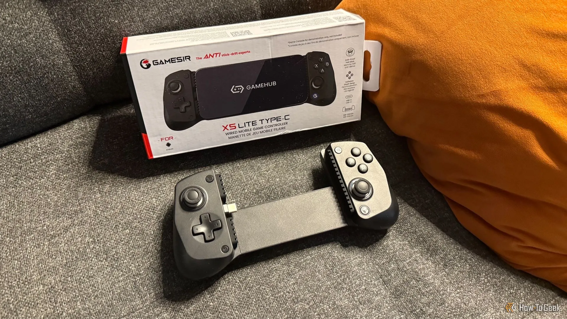 Bộ điều khiển chơi game GameSir X5 Lite cùng hộp sản phẩm đặt trên ghế sofa