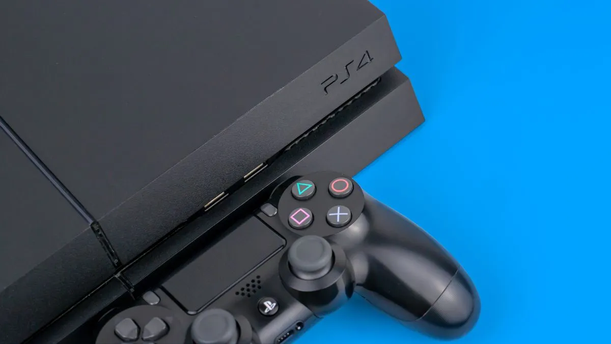 Console Sony PS4 màu đen và bộ điều khiển DualShock đặt cạnh nhau trên nền xanh.