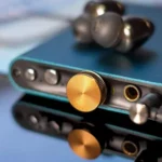 DAC di động iFi Hip-DAC màu xanh ngọc đặt trên điện thoại thông minh, minh họa cho DAC và amp ngoài gọn nhẹ.