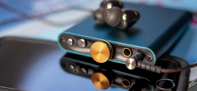 DAC di động iFi Hip-DAC màu xanh ngọc đặt trên điện thoại thông minh, minh họa cho DAC và amp ngoài gọn nhẹ.