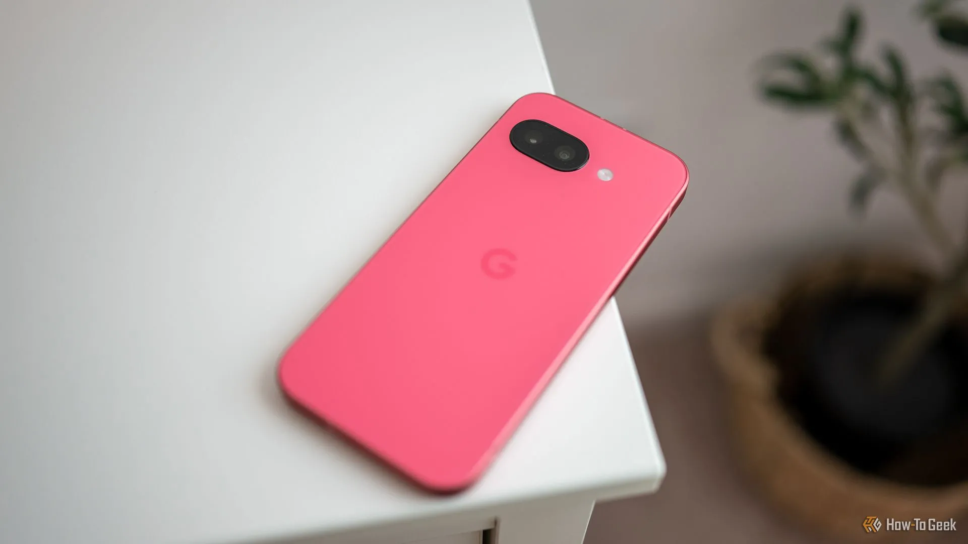 Điện thoại Google Pixel 9a đặt trên mặt bàn, hiển thị thiết kế tối giản không có cụm camera lồi.
