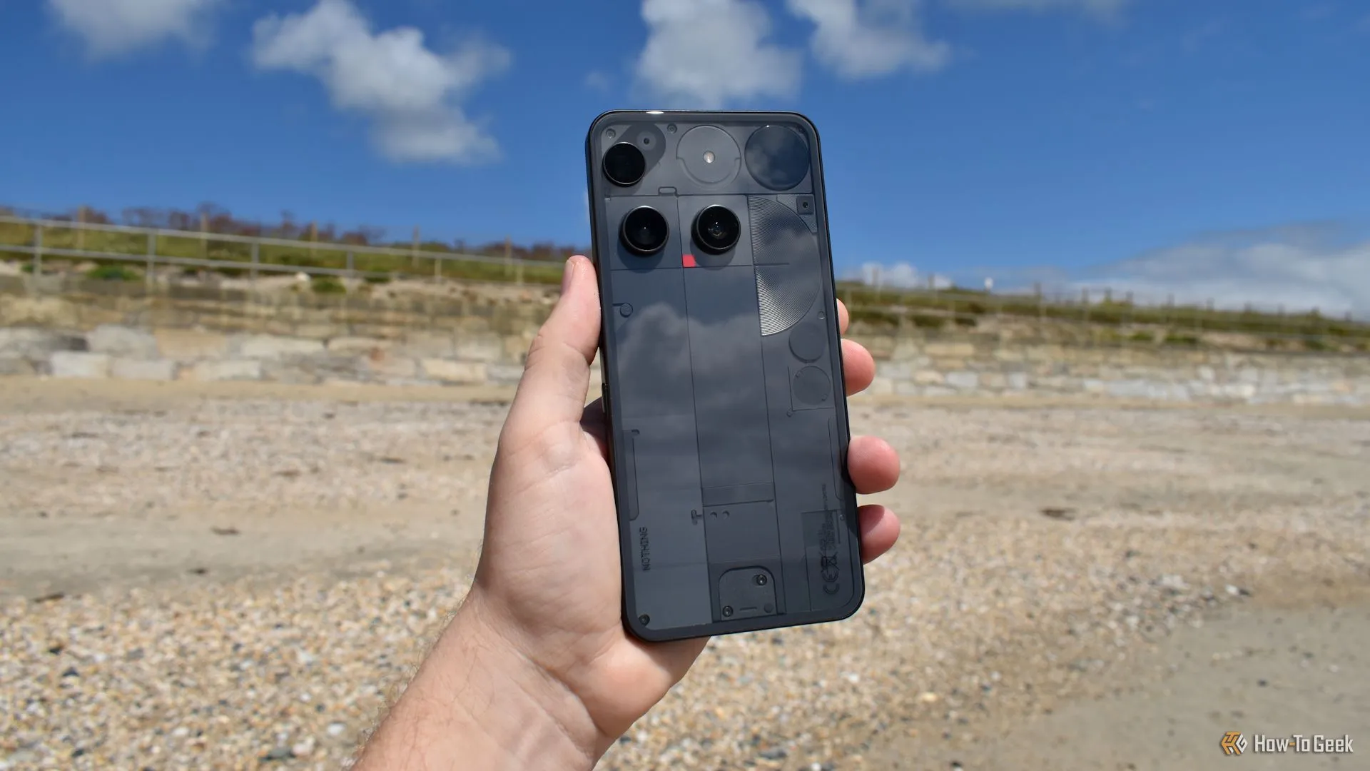 Điện thoại Nothing Phone (3) trong tay người dùng tại bãi biển, thể hiện kích thước và trải nghiệm cầm nắm