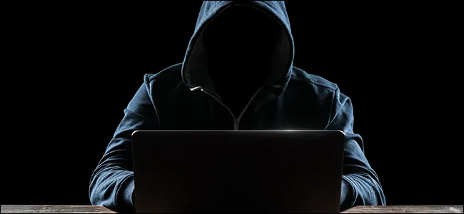 Hacker đội mũ trùm đầu trước máy tính, minh họa nguy cơ lừa đảo (phishing) và tấn công mạng từ trình quản lý mật khẩu.