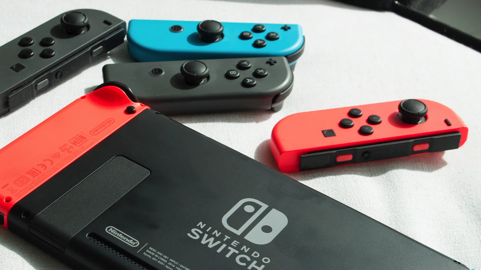 Hai cặp tay cầm Joy-Con và một máy console Nintendo Switch thế hệ trước.