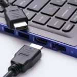 Hai đầu cáp HDMI gần cổng HDMI của laptop hiện đại trên nền trắng