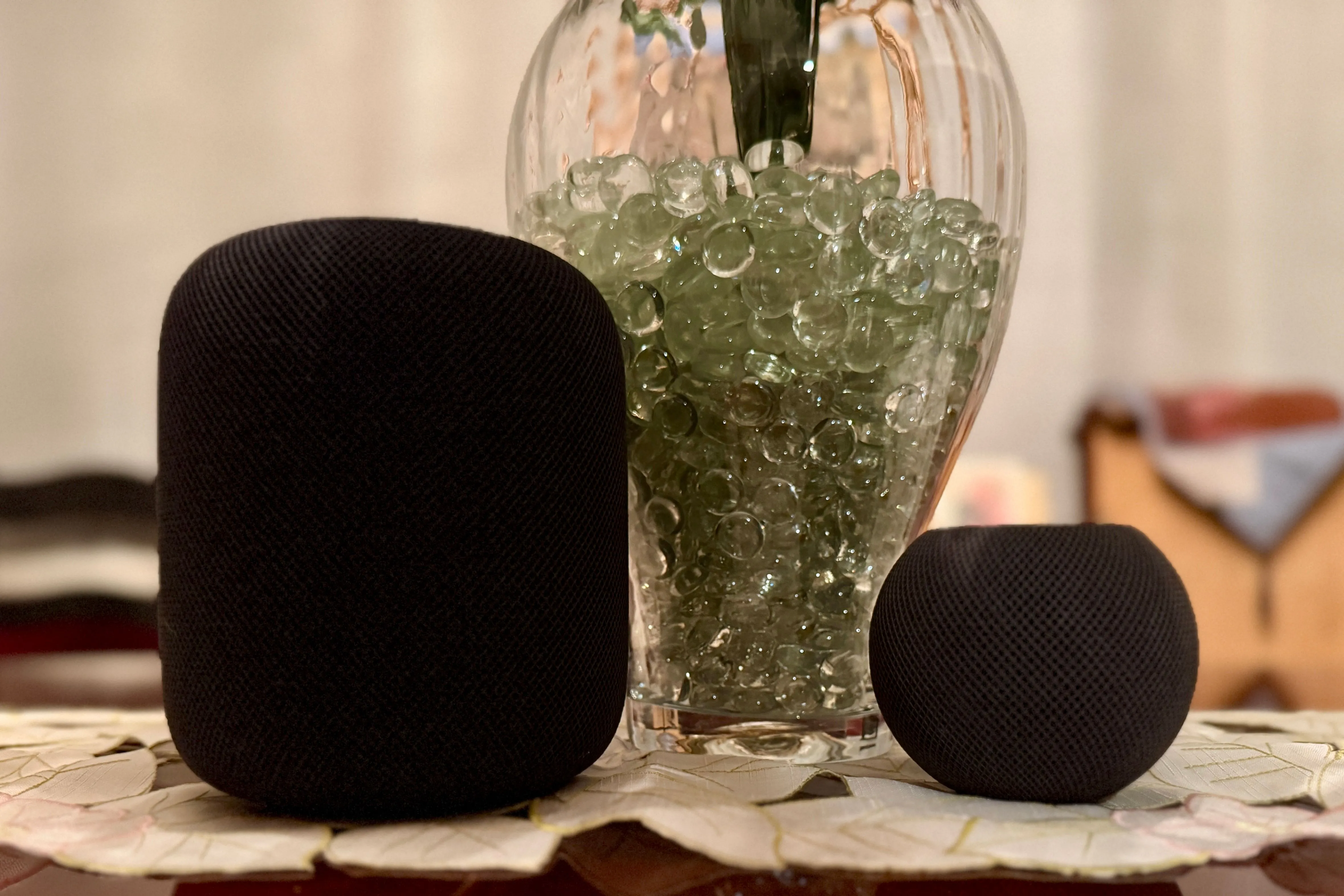 Hai loa HomePod màu đen đặt cạnh một lọ hoa trang trí, thể hiện sự hòa nhập của loa vào không gian nội thất hiện đại.