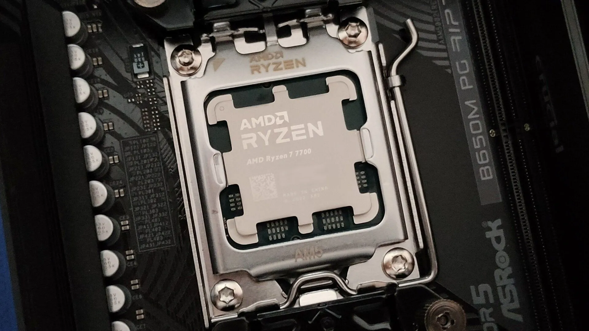 Hình ảnh cận cảnh bộ vi xử lý AMD Ryzen 7 7700 được lắp vào socket AM5 trên bo mạch chủ ASRock B650M PG Riptide, minh họa quá trình lắp đặt linh kiện PC.