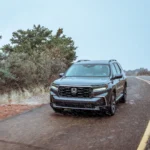 Hình ảnh cận cảnh chiếc Honda Pilot TrailSport 2023 đang di chuyển trên con đường nông thôn quanh co.