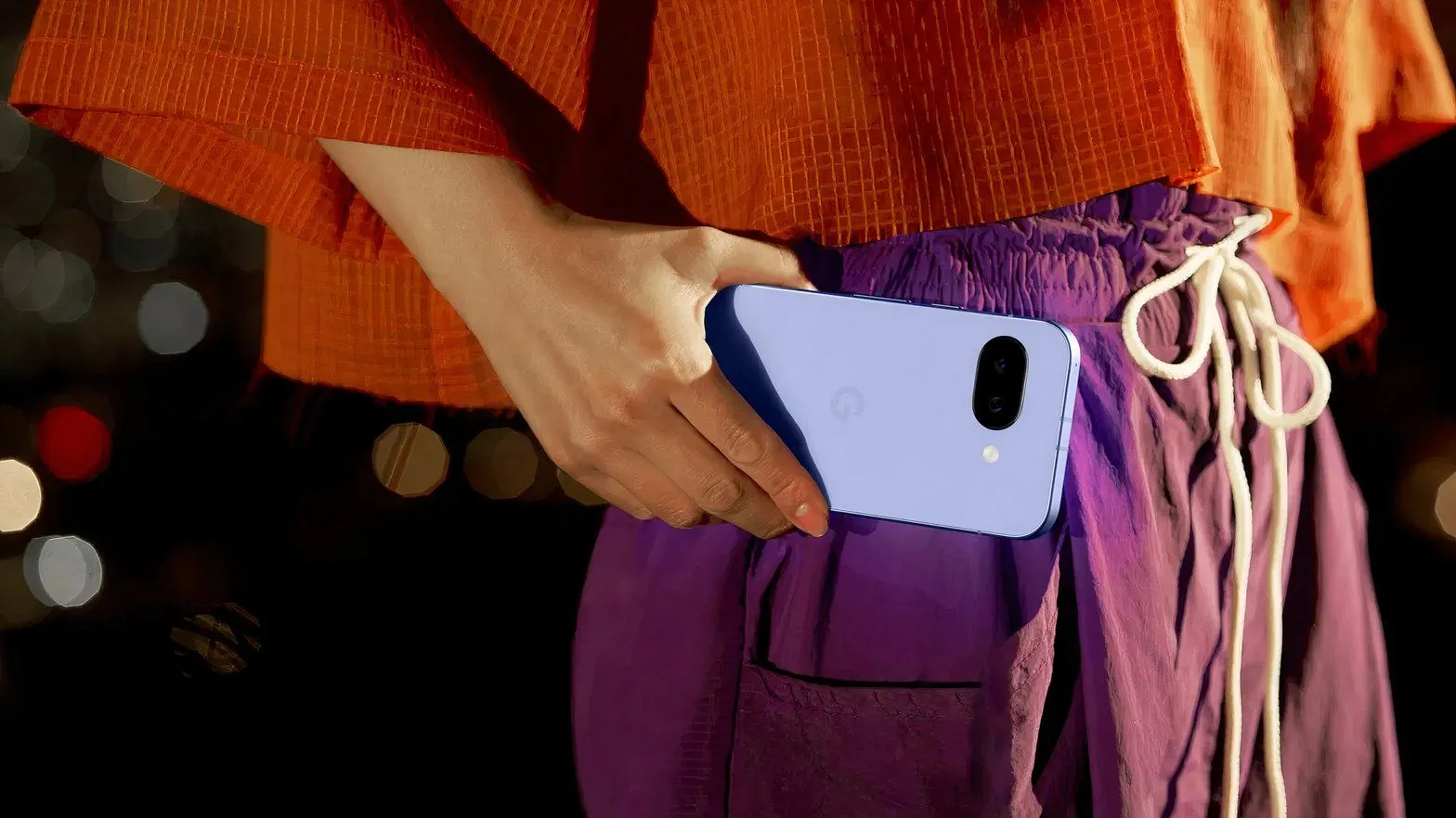 Hình ảnh cận cảnh người phụ nữ đang cầm Google Pixel 9a ở ngang eo, cho thấy kích thước và cách cầm nắm.