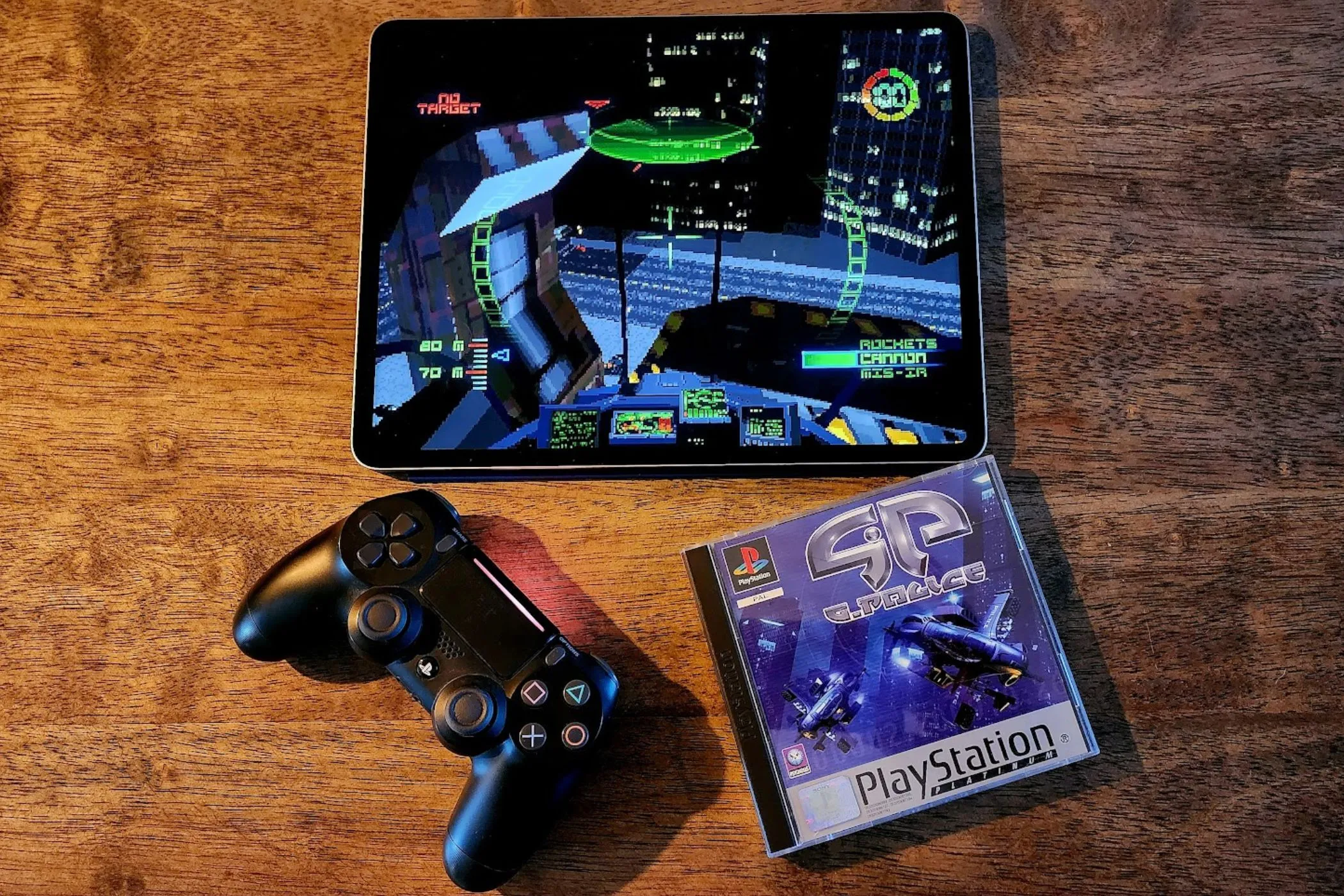 iPad đang chạy game G-Police, bên cạnh đĩa game gốc và tay cầm PS4, thể hiện khả năng giải trí mạnh mẽ.
