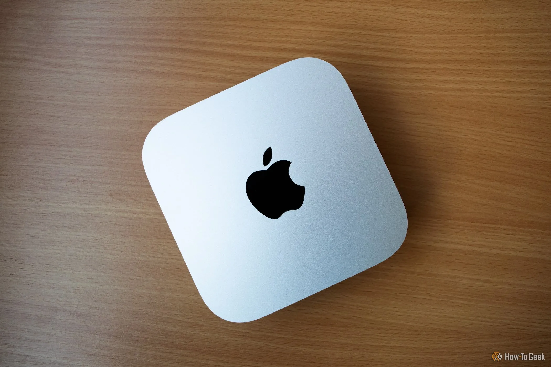 Mac Mini M4 màu bạc đặt trên bàn gỗ đơn giản, thể hiện sự tinh tế.