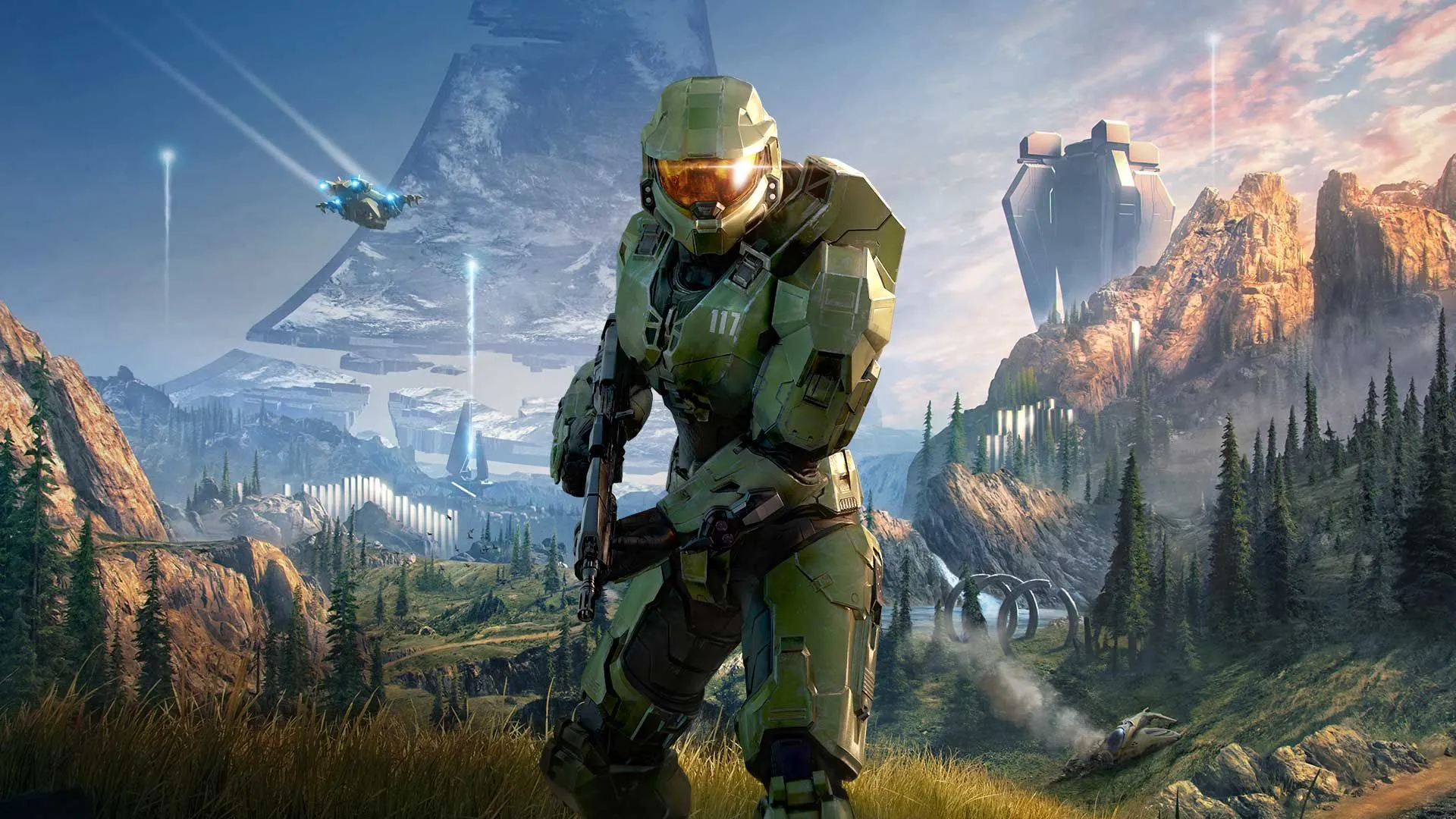 Master Chief holding a weapon in a grass and forested area on the ring in Halo Infinite
