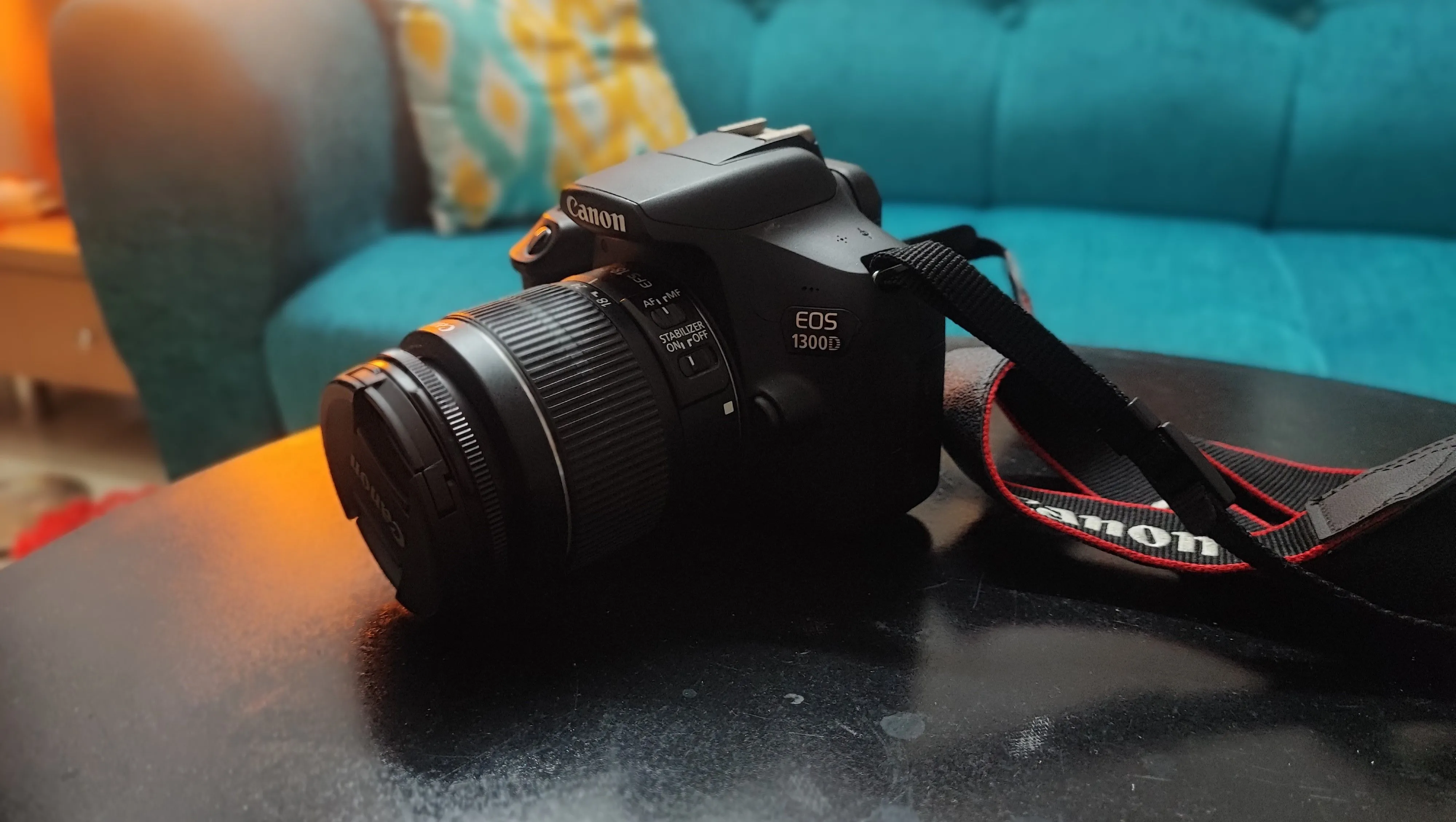 Máy ảnh DSLR Canon EOS 1300D màu đen với ống kính kit, đặt trên mặt phẳng sáng, thể hiện lựa chọn tối ưu cho nhiếp ảnh chuyên nghiệp thay vì smartphone đắt tiền.