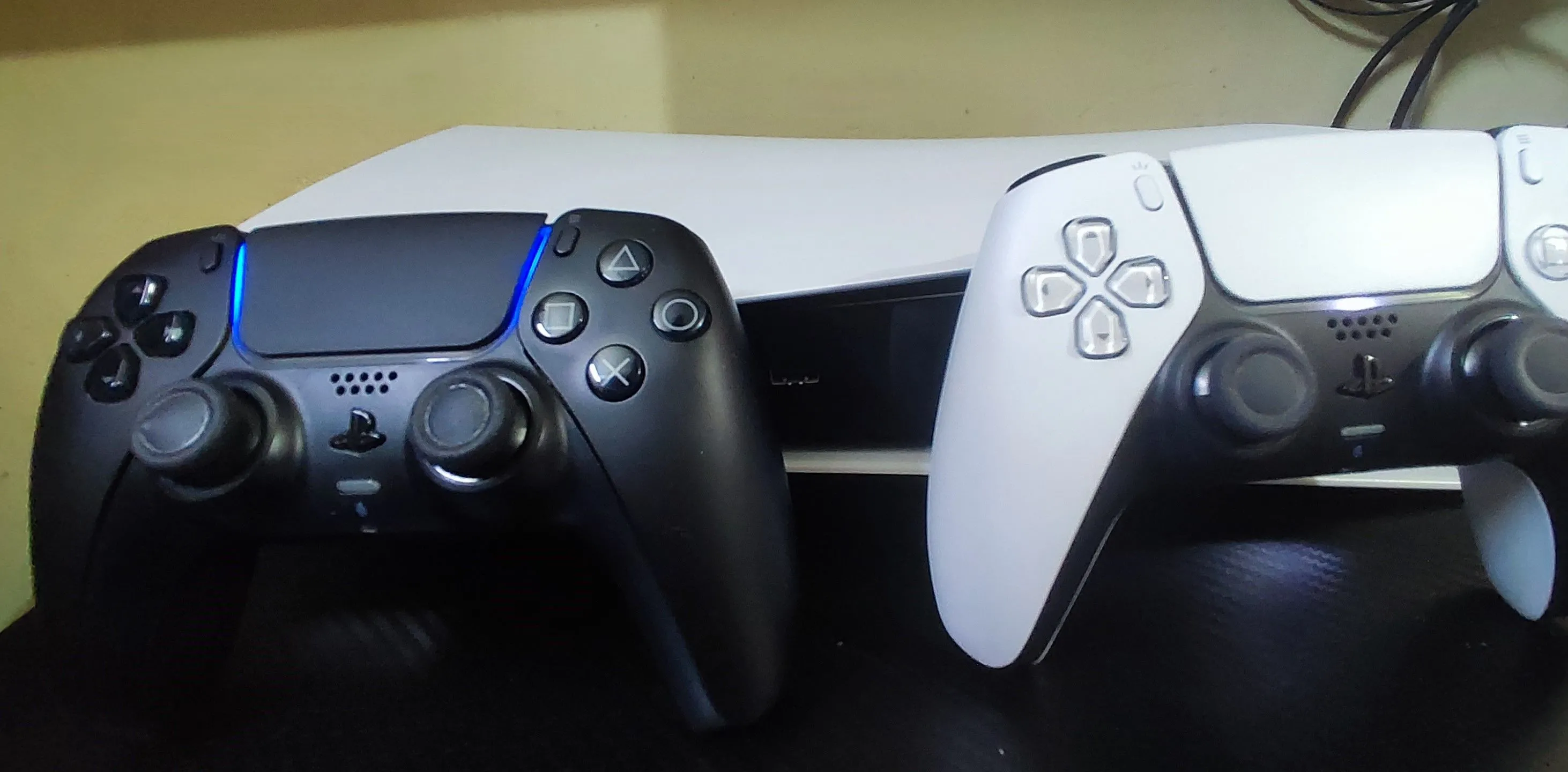 Máy chơi game PlayStation 5 màu trắng đen đặt cùng hai tay cầm DualSense, biểu trưng cho thiết bị giải trí chuyên biệt giúp kiểm soát thời gian chơi game.