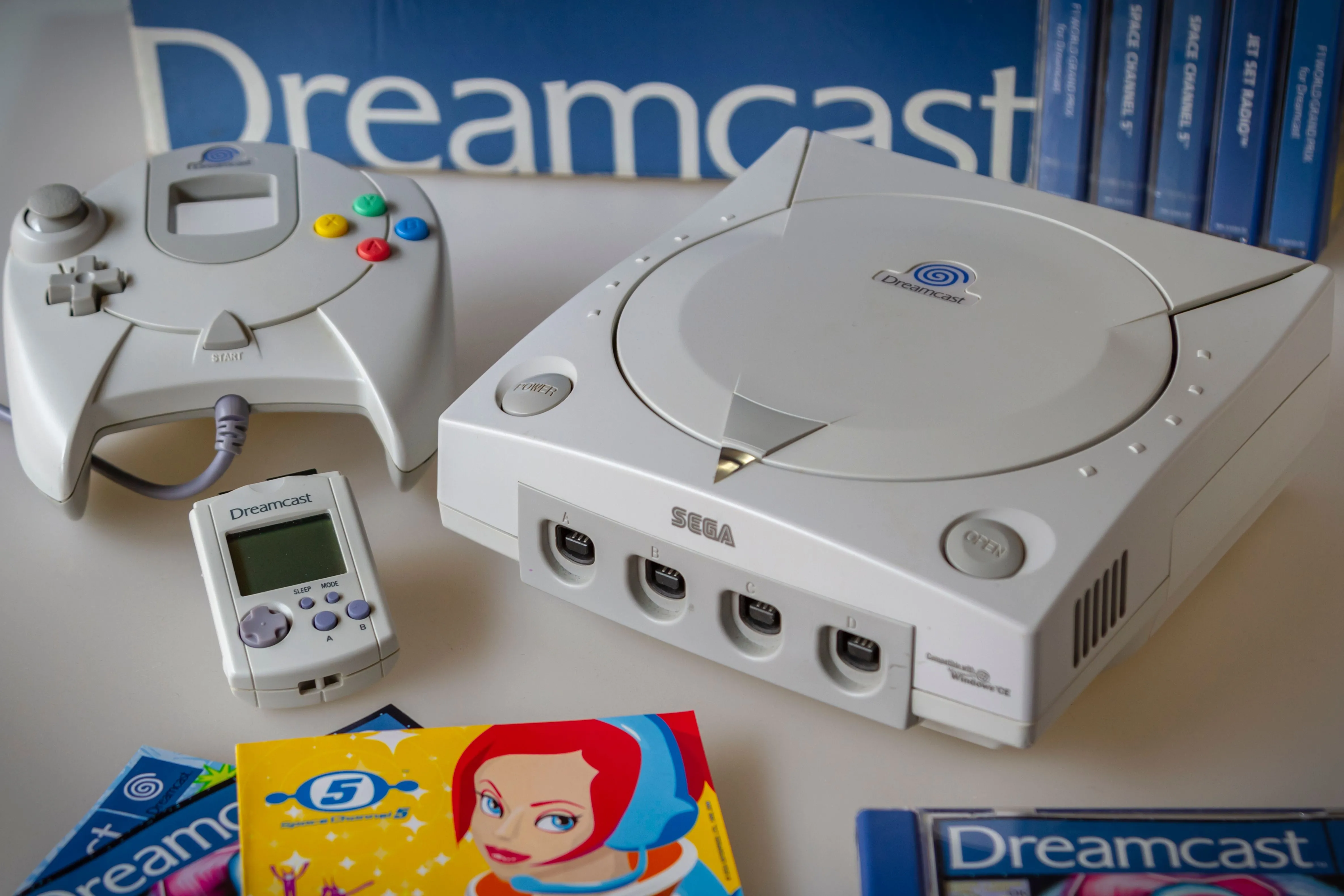 Máy chơi game Sega Dreamcast cùng bộ điều khiển, VMU và đĩa game Space Channel 5, đại diện cho kỷ nguyên game sáng tạo và đa dạng.