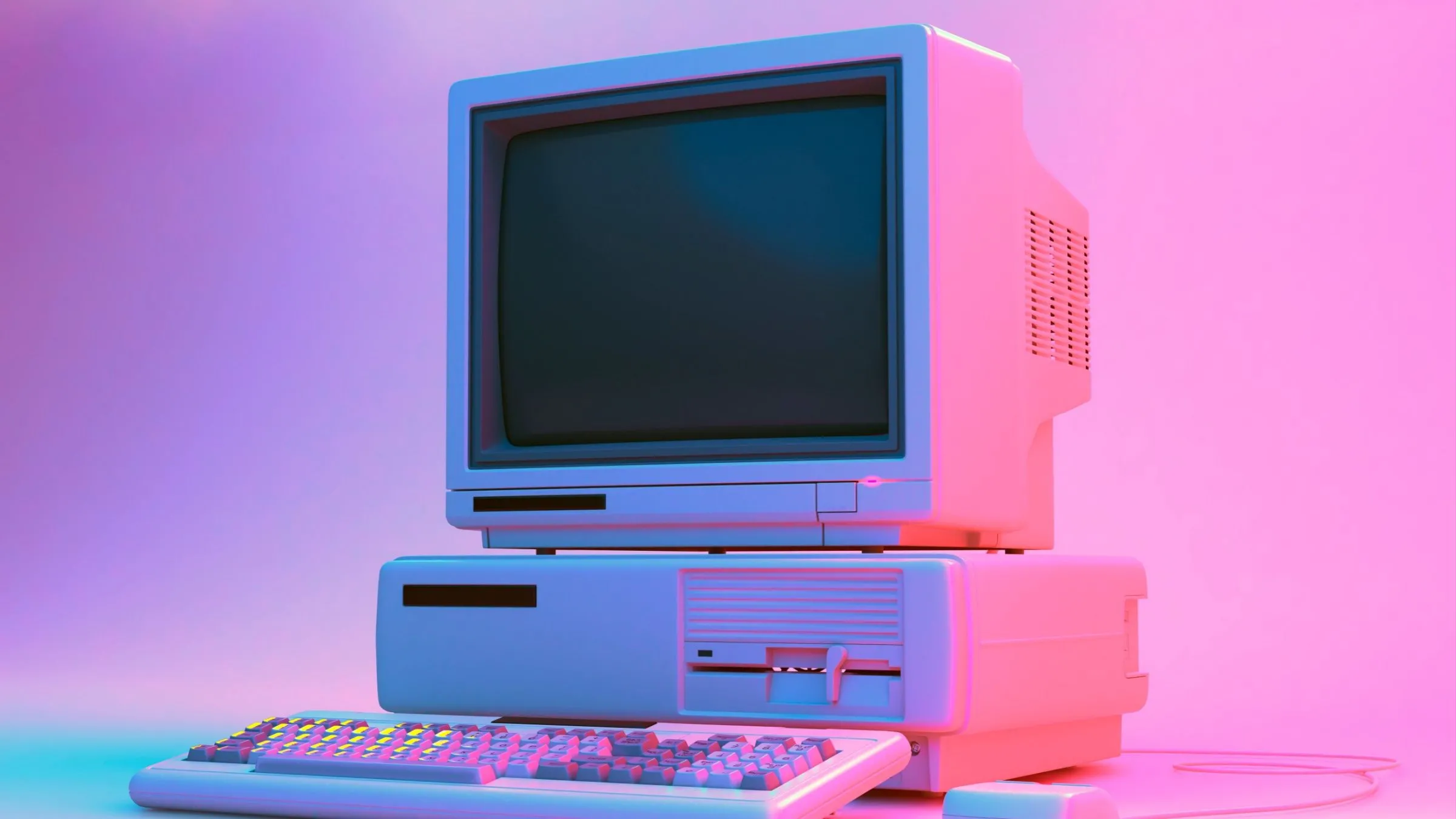 Một bộ máy tính để bàn cổ điển với ổ đĩa mềm, bàn phím và chuột trong ánh sáng neon, tượng trưng cho tính năng đa dụng của PC.