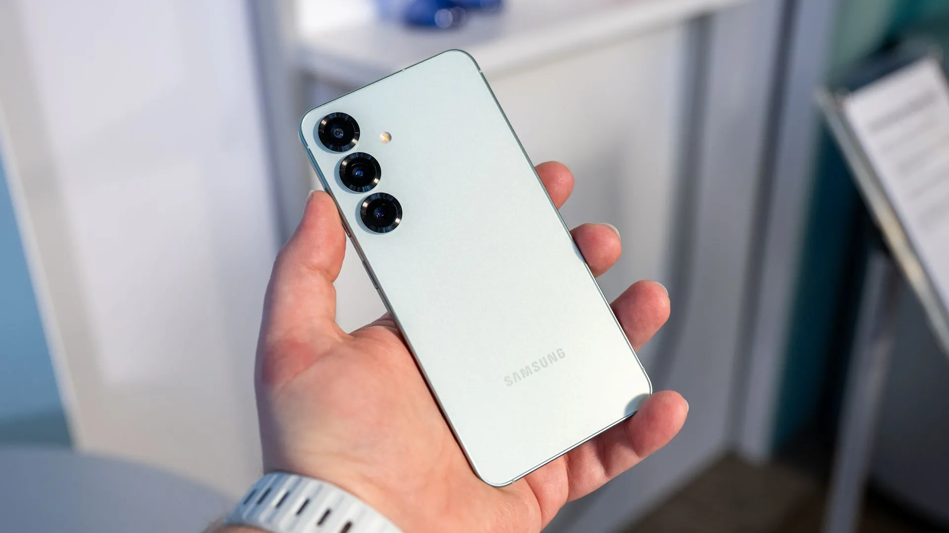 Một người đang cầm Samsung Galaxy S25 và nhìn vào cụm camera sau, làm nổi bật khả năng chụp ảnh selfie thông minh.