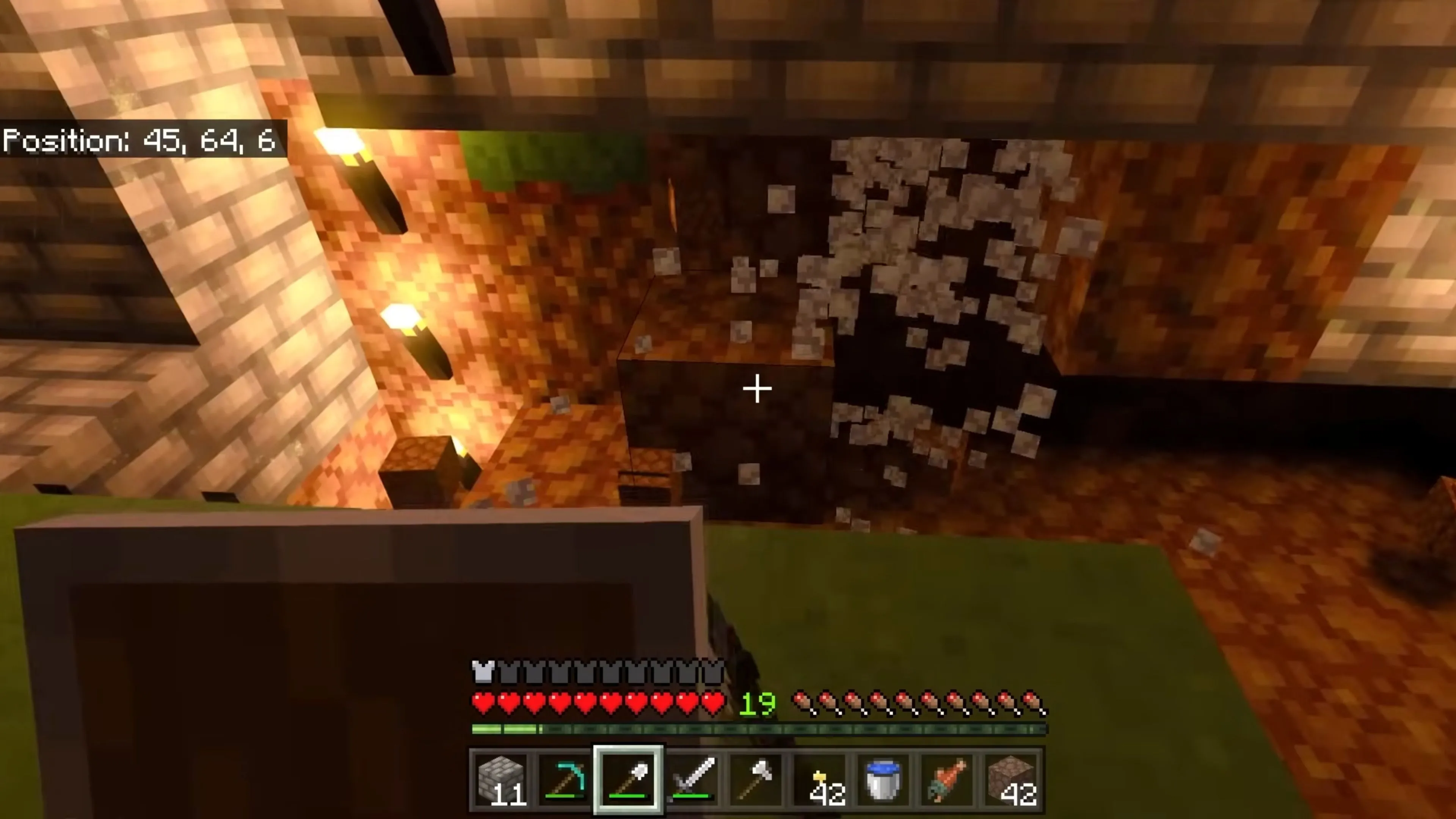 Người chơi Minecraft đang khai thác tài nguyên trong một hang động tối tăm, ánh sáng duy nhất đến từ ngọn đuốc cầm tay.