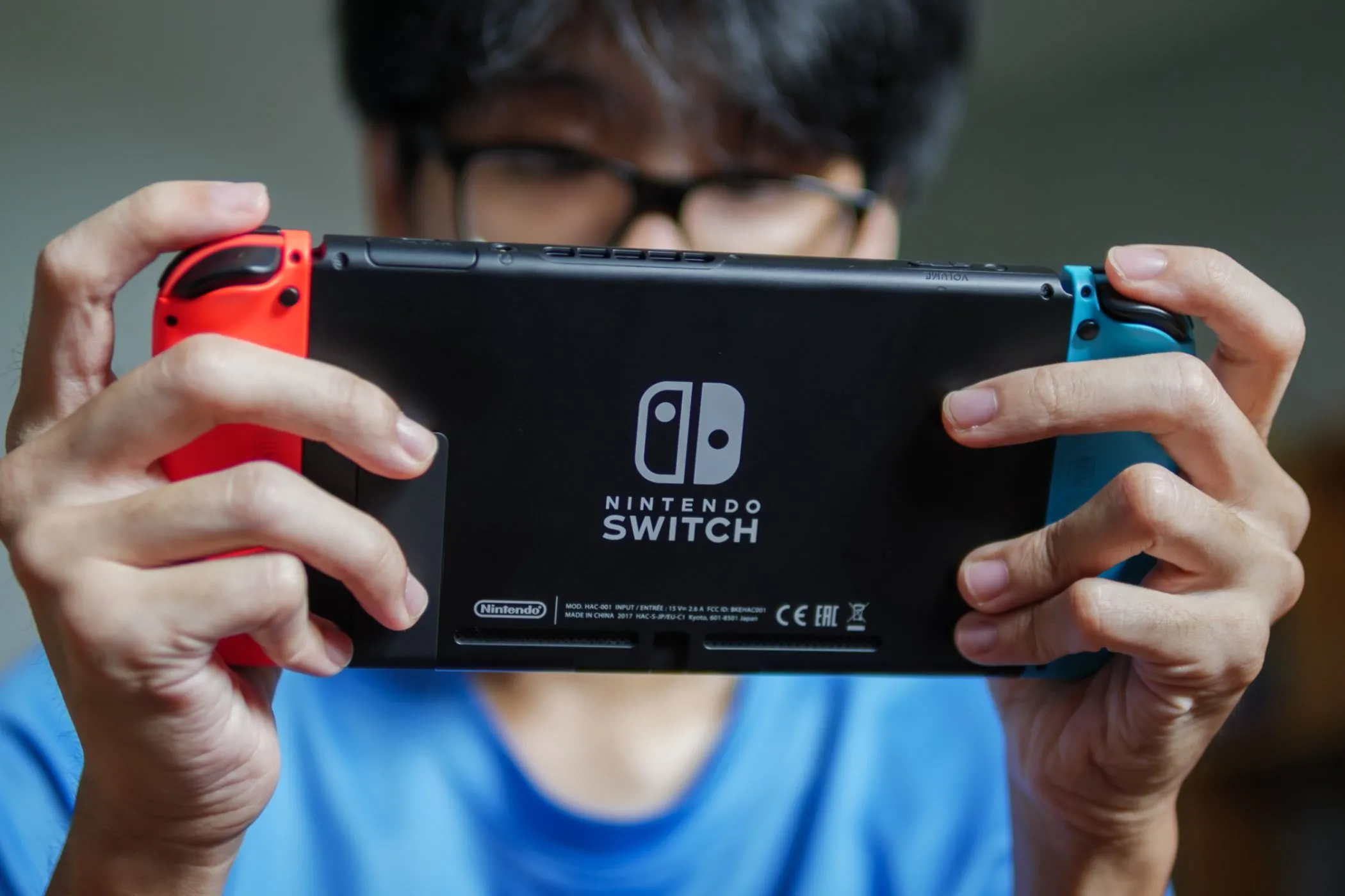 Người đàn ông đang chơi game trên máy Nintendo Switch ở chế độ cầm tay, thể hiện sự tiện lợi khi di chuyển.