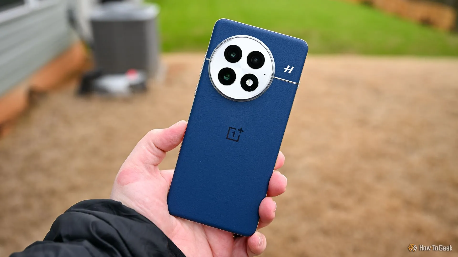 Người dùng cầm điện thoại OnePlus 13 màu xanh lam, khoe thiết kế mặt lưng và cụm camera, minh họa công nghệ pin silicon-carbon.
