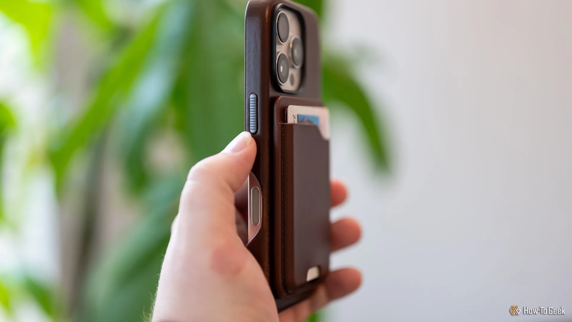 Người dùng cầm ví Nomad Leather Mag Wallet đang gắn chặt vào mặt lưng iPhone, thể hiện trải nghiệm sử dụng thực tế.