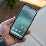 Người dùng đang cầm chiếc Google Pixel 8a màu đen, hiển thị màn hình chính cùng viền màn hình và camera selfie đục lỗ