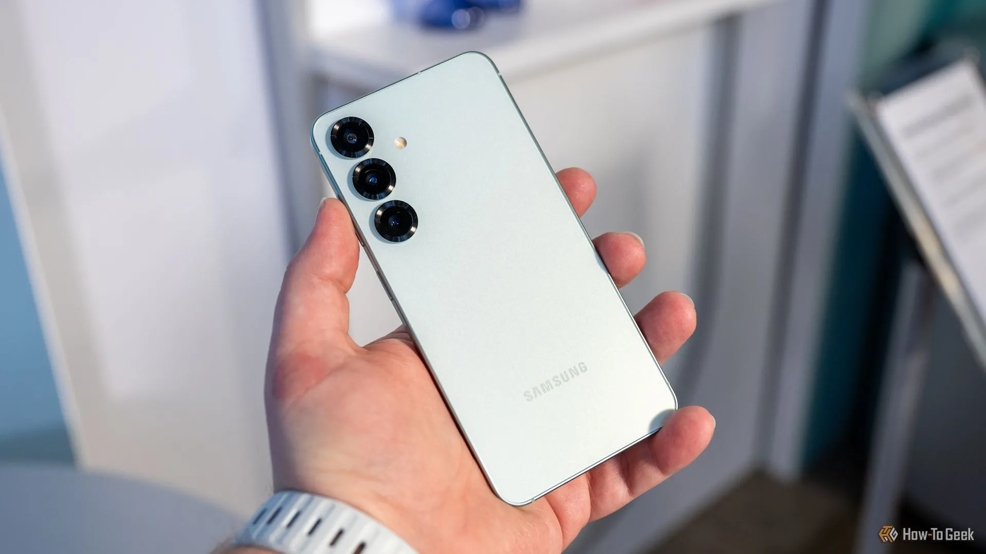 Người dùng đang cầm chiếc Samsung Galaxy S25 và nhìn vào cụm camera sau