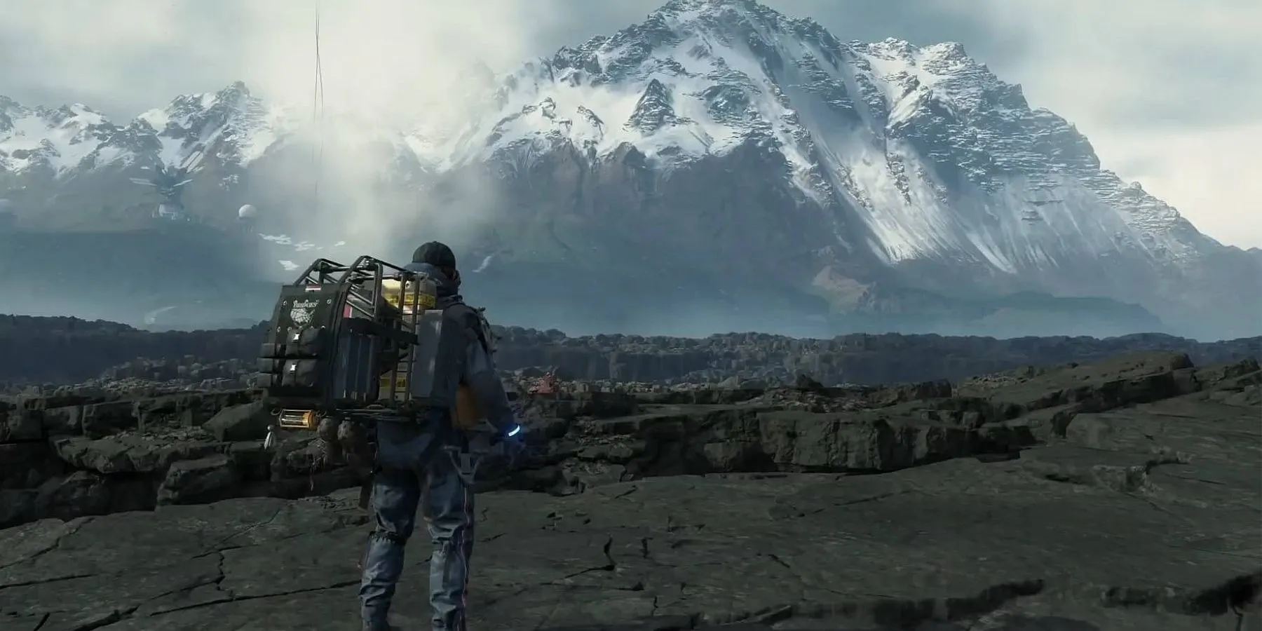 Người vận chuyển Sam Porter Bridges với khối lượng hàng hóa lớn trên lưng trong tựa game Death Stranding.