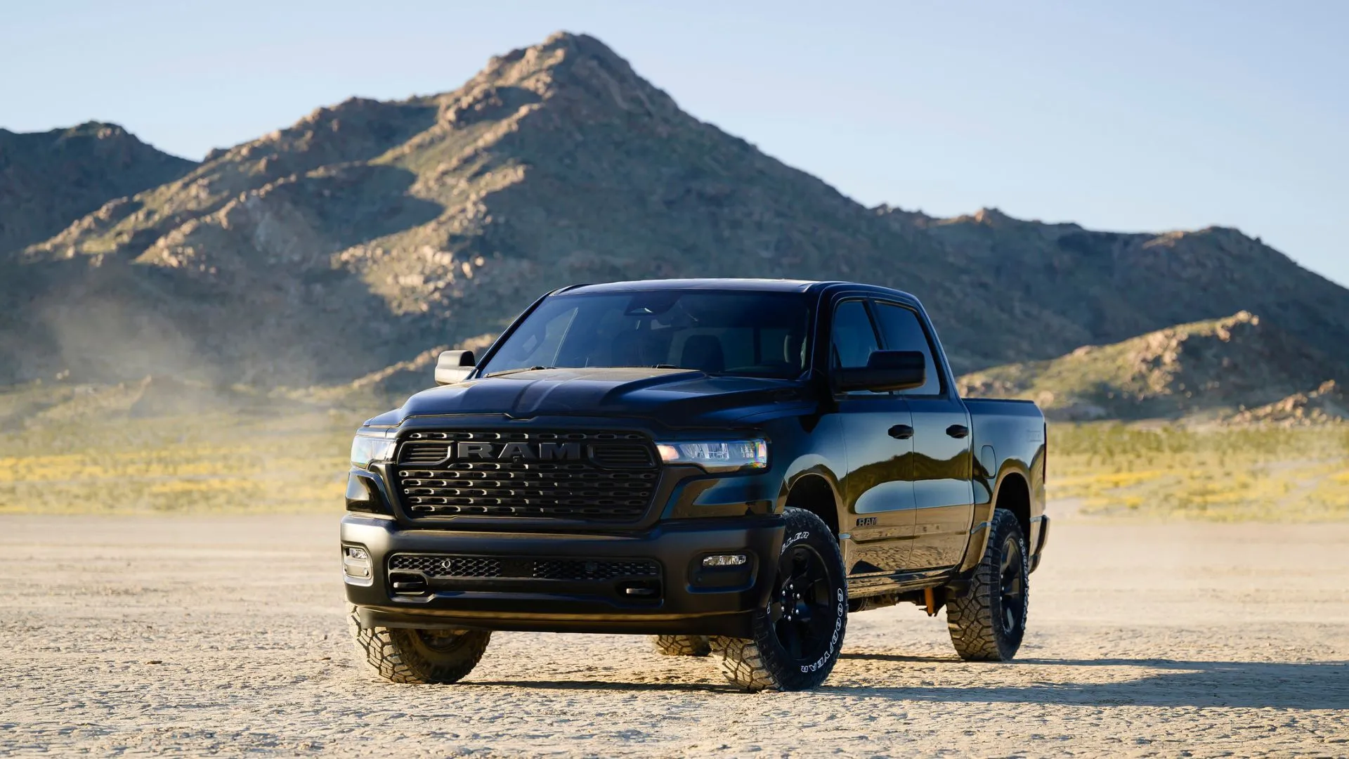 Ram 1500 Warlock 2025 màu đen đỗ trên nền sỏi với núi phía sau