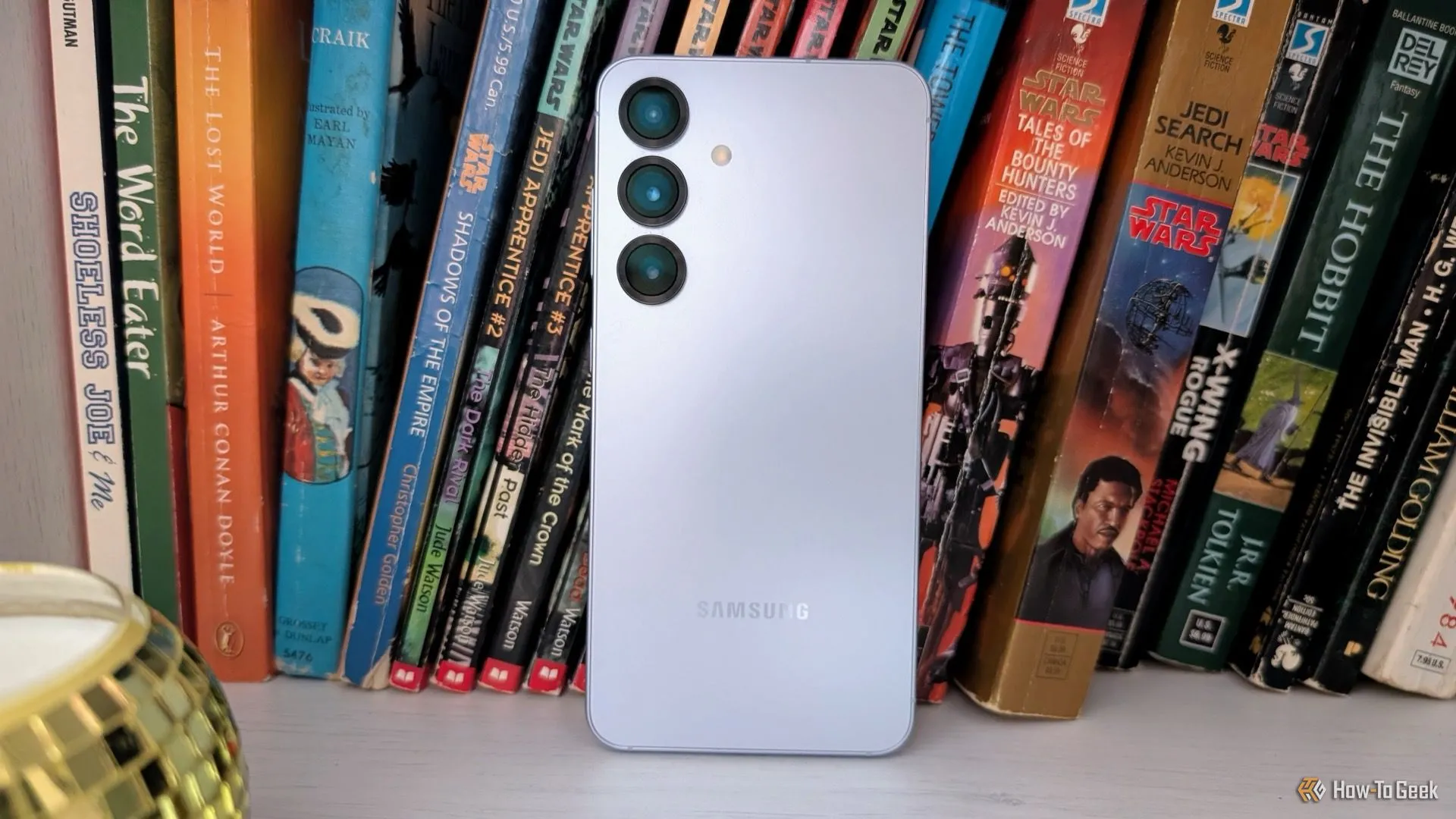 Samsung Galaxy S25 màu xanh băng đặt trên kệ thể hiện kích thước nhỏ gọn
