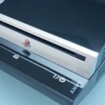 Sony PlayStation 3 đời đầu màu đen, cận cảnh, trên nền tối.
