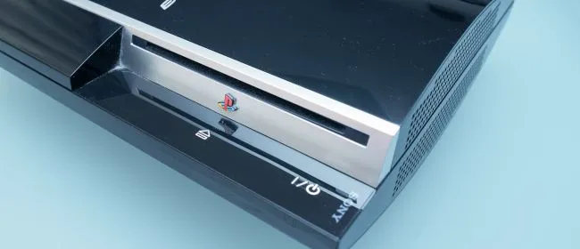 Sony PlayStation 3 đời đầu màu đen, cận cảnh, trên nền tối.