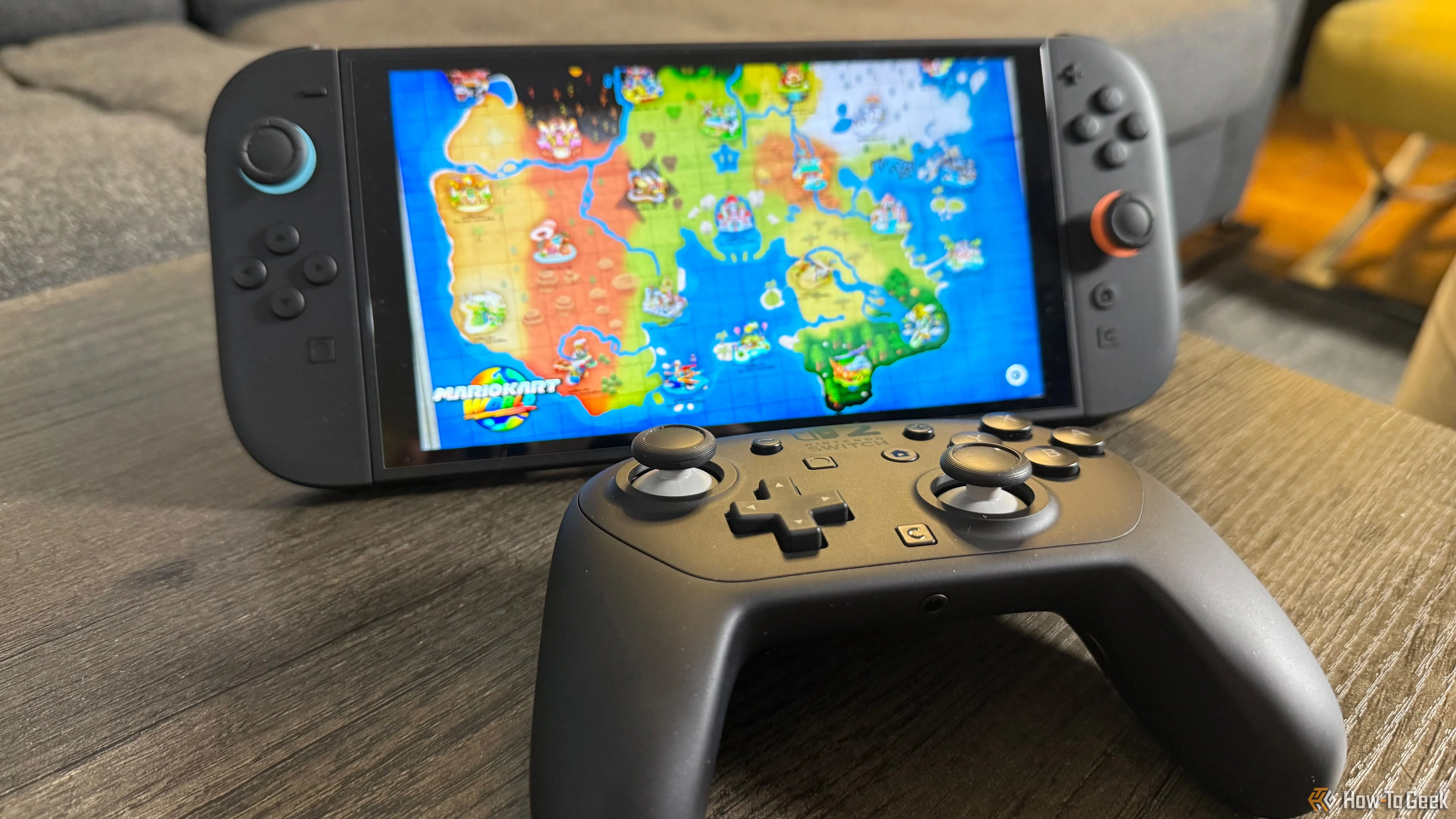 Tay cầm Nintendo Switch 2 Pro nằm cạnh máy Switch 2 đang hiển thị trò chơi Mario Kart World, minh họa trải nghiệm chơi game mượt mà