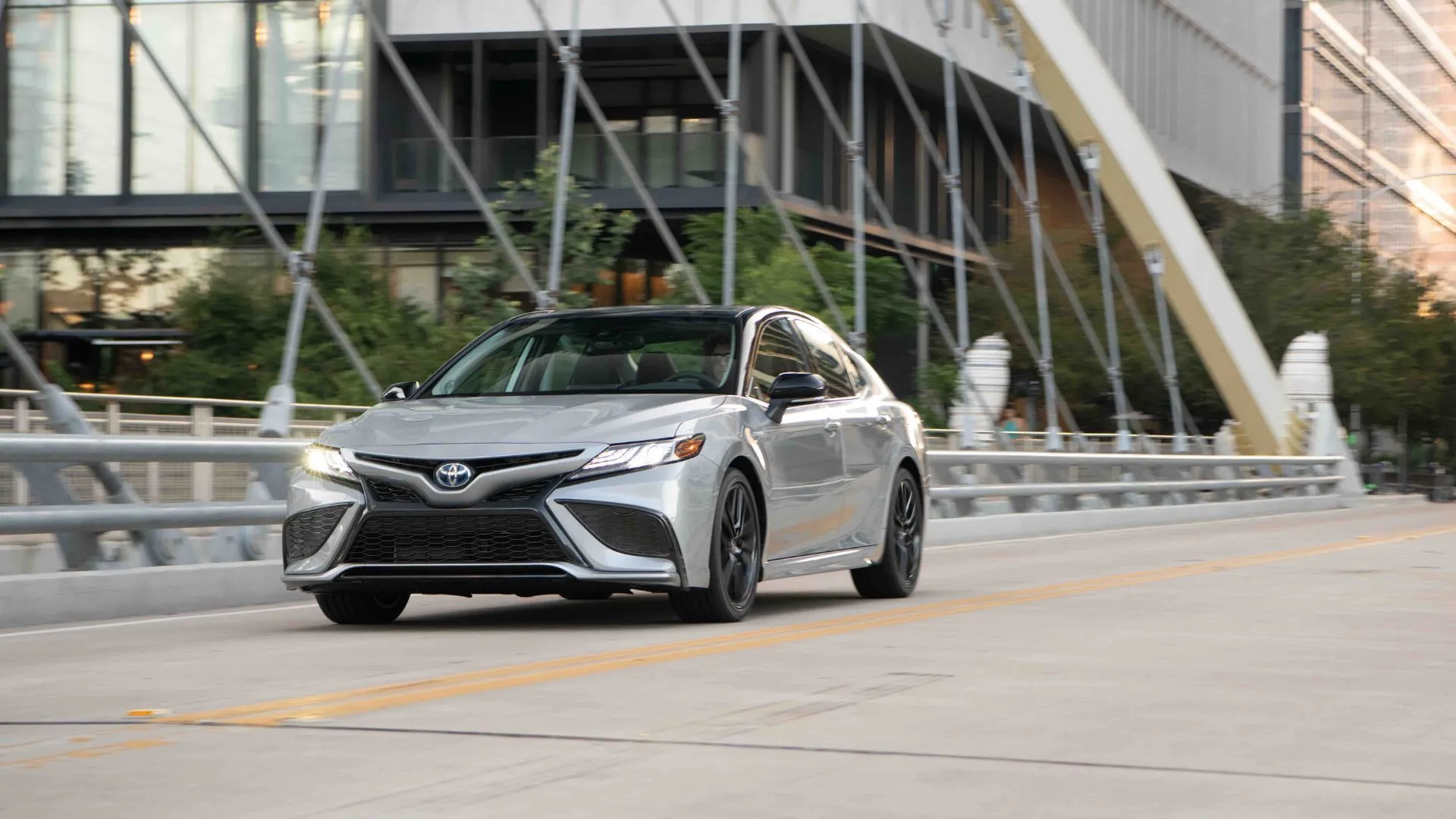 Xe Toyota Camry 2022 màu bạc đang chạy trong thành phố.